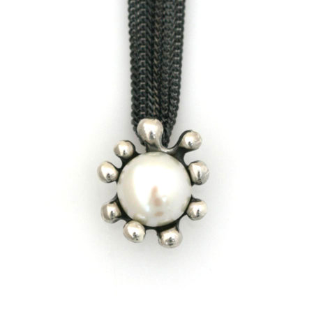 Halskæde med søanemone vedhæng og hvid perle i sorte kæder. Håndlavet af Christel Kaaber Guldsmedie