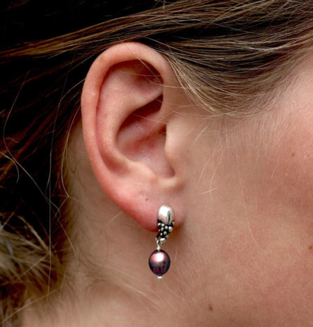 Dråbe øreringe til kvinder i sølv med mørk perle set på mode.