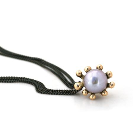 Søanemone halskæde i guld med grå perle set liggende. Håndlavet af Christel Kaaber Guldsmedie